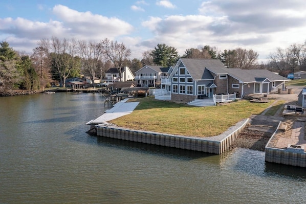 A lakeside property with a dock, a grassy area, and multiple houses with distinct architectural styles.