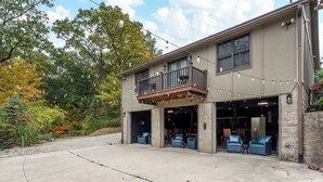 A two-story building with a balcony, open garage doors, and outdoor seating. - Private I Pool Table I Bar I Studio I House I Roku (Westerville)
