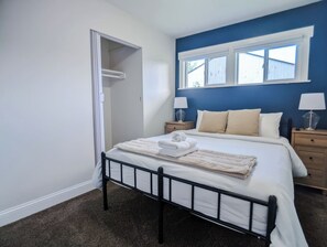 Une chambre à coucher avec un lit, des tables de chevet, une fenêtre et une porte.