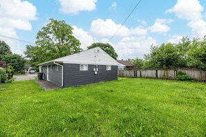 Une maison de plain-pied avec un toit en pente, un porche à l’avant et une cour arrière clôturée.