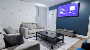 Ein Wohnzimmer mit einer Couch, einem Couchtisch, einem Fernseher und einer Tür.