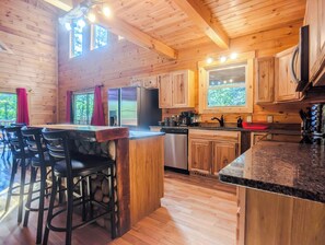 Un interior de madera con cocina, taburetes de bar y una mesa de comedor.