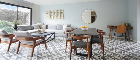 A modern living room with a dining area, a sofa, a coffee table, and a dining table with chairs.