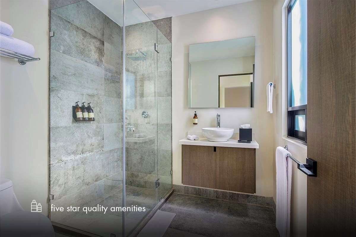 Un baño moderno con cabina de ducha de vidrio, un lavabo con espejo grande y un perchero para toallas.
