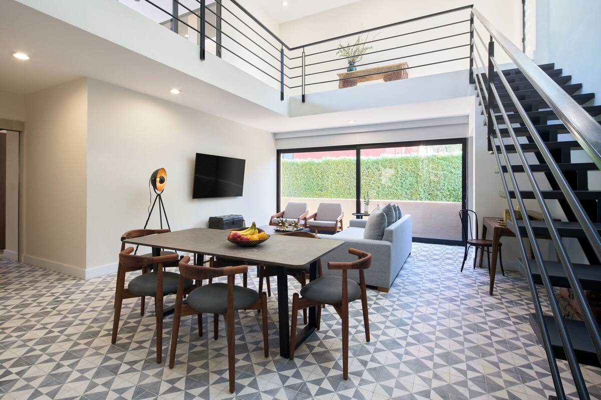 Ein modernes Interieur mit Essbereich, Treppe und großem Fenster.