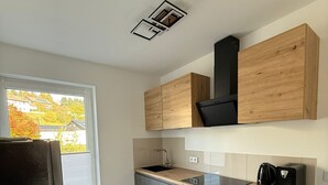 A modern kitchen with a built-in oven, a coffee maker, and a toaster on the countertop. - StayEasy Accommodation (Gummersbach)