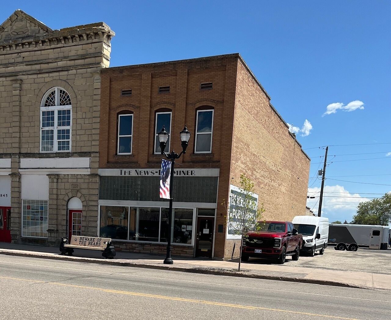 A two-story building with a brick facade, a storefront labeled "THE NEWS-MINER," and a sign reading "BEWARE OF THE BEARS."