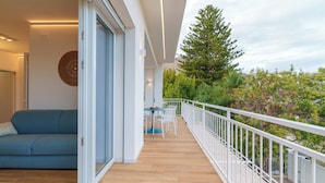 Ein Balkon mit Holzboden, weißem Geländer und einer blauen Couch.