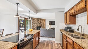 Eine moderne Küche mit Granit Arbeitsplatten, Holzschränken, einem eingebauten Ofen und einer Wand mit Steinverkleidung.