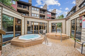 A spa area with two hot tubs and a stone-tiled floor. - Park Place 202E: Breck Condo Near Snowflake Lift, Fireplace, Multiple Hot Tubs (Breckenridge)