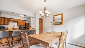 Eine moderne Küche mit Holzausstattung, einer zentralen Kochinsel und einem Essbereich mit Holztisch und Stühlen.