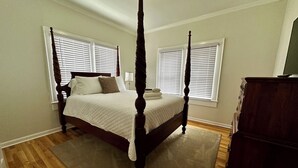 Un lit à baldaquin avec une couvre-lit matelassé, deux tables de chevet avec des lampes et une commode.