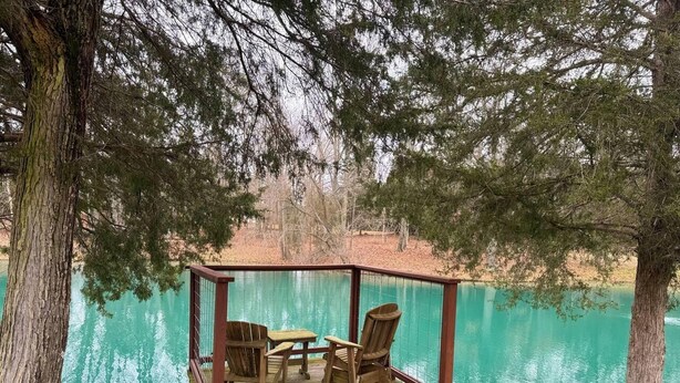 Een houten terras met een tafel en stoelen, uitkijkend op een waterpartij.