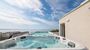 A rooftop with two hot tubs overlooking a body of water.