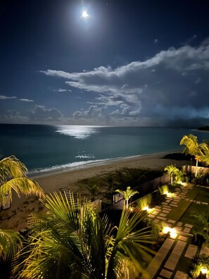 A nighttime beach scene with a clear view of the ocean and a moonlit sky. - Allure 302: 2BR Beachfront Condo with Infinity Pool, Sun Deck, Gym, Fire Pit etc (Bridgetown)