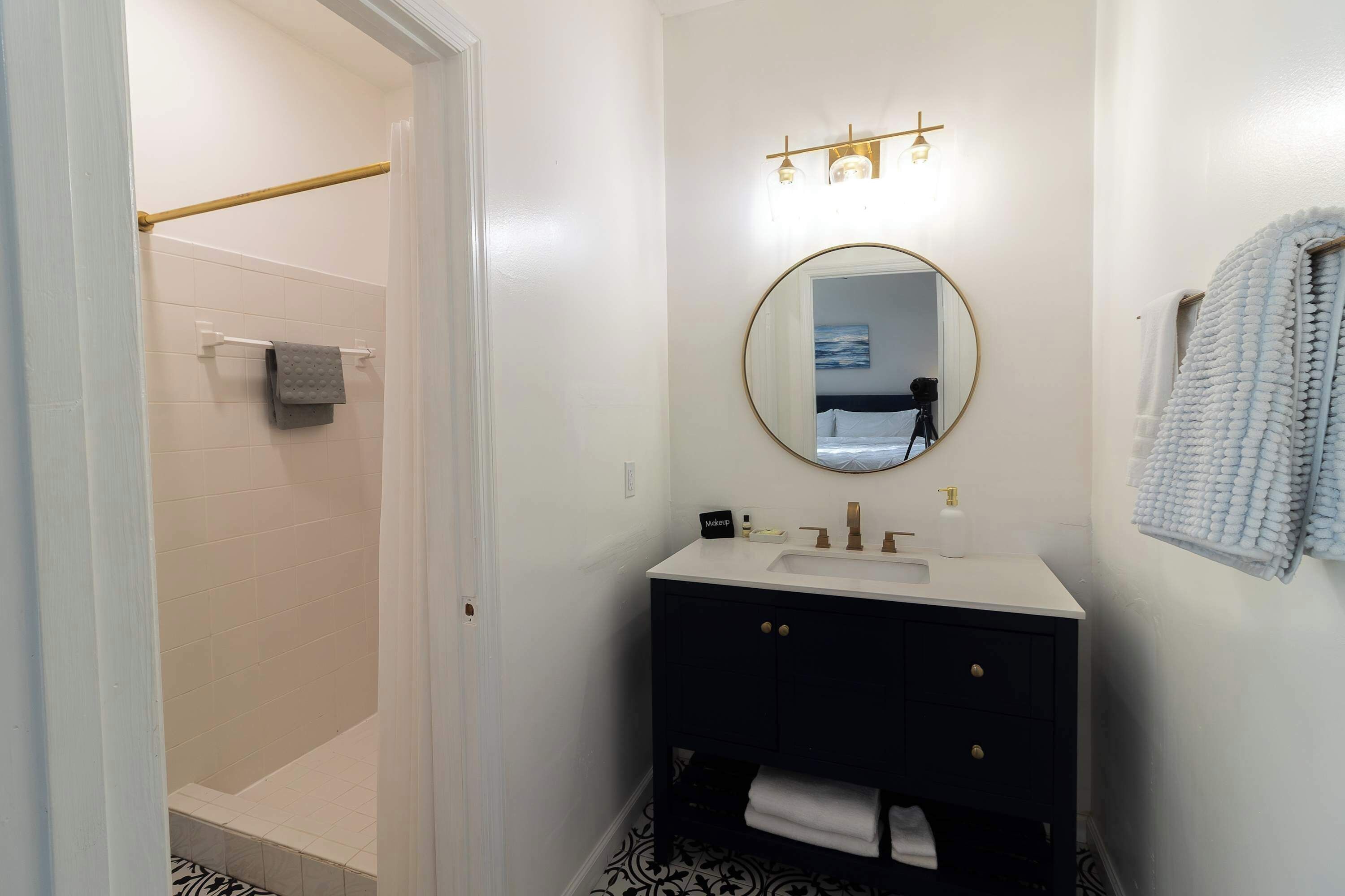A bathroom with a white sink, black vanity, and a mirror above it.