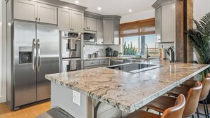 Una cocina moderna con electrodomésticos de acero inoxidable, encimera de mármol y una isla grande con taburetes de bar.
