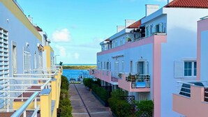 Une rangée d’immeubles modernes dotés de balcons, un ciel dégagé et une vue sur la mer.