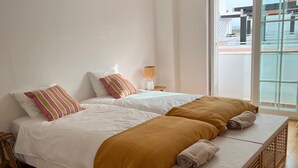 Une chambre à coucher avec un lit, une table de chevet, une lampe et une fenêtre.