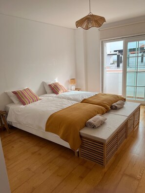 Ein Schlafzimmer mit Bett, Nachttisch, Lampe und Fenster.