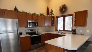 Une cuisine moderne avec des meubles en bois, des appareils en acier inoxydable, un grand îlot central et une vue sur l’extérieur.