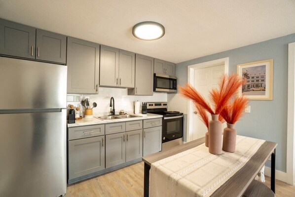 A modern kitchen with grey cabinets, stainless steel appliances, and a dining area with a table set for two.