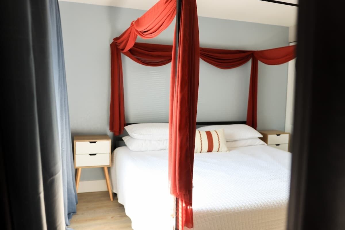Ein Schlafzimmer mit Himmelbett, Nachttisch und Beistelltisch.