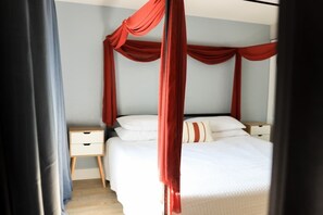 A bedroom with a canopy bed, a bedside table, and a nightstand.