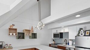 A modern kitchen with a large island, wooden cabinets, and a hanging light fixture. - Slope-Side| Modern Remodel | Hot Tub | Park Free (Park City)