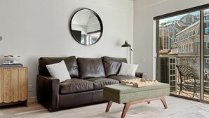 A modern living room with a brown leather sofa, a round mirror, and a wooden coffee table. - Slope-Side| Modern Remodel | Hot Tub | Park Free (Park City)