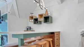 A modern kitchen with wooden stools, a central island, and built-in shelves. - Slope-Side| Modern Remodel | Hot Tub | Park Free (Park City)