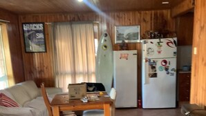 A wooden interior with a dining area, a sofa, and a refrigerator. - Surfrise manyana the surfers temple.sunrise ocean views native wildlife, (Manyana)