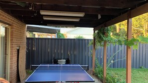 A ping pong table under a covered area with a brick wall and a wooden fence in the background. - Surfrise manyana the surfers temple.sunrise ocean views native wildlife, (Manyana)