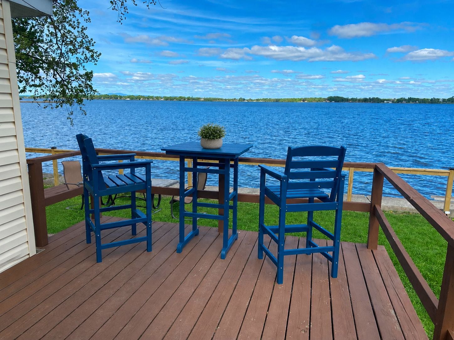 A wooden deck with a table and two chairs overlooking a body of water.