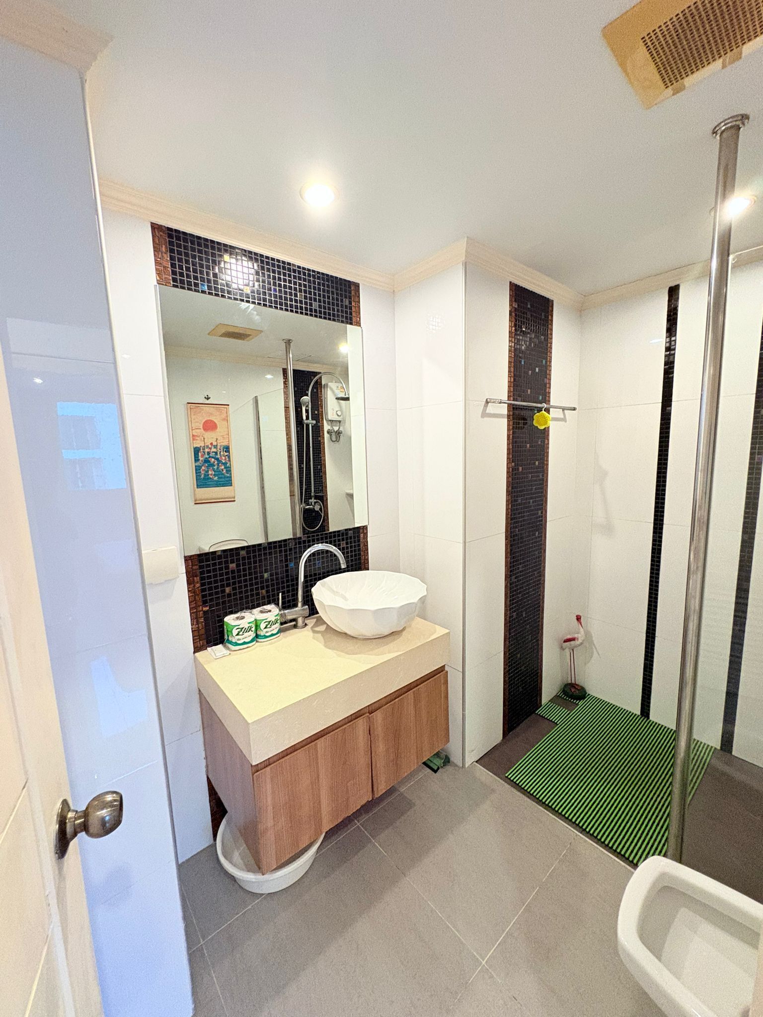 Un baño moderno con un lavabo blanco, un espejo grande y una zona de ducha.