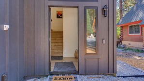L’entrée d’un chalet, avec une porte en bois, un paillasson et une vue sur l’intérieur.