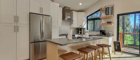 A modern kitchen with white cabinets, stainless steel appliances, and a large island with bar stools.