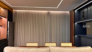 A modern interior with a dining area, a sofa, and a kitchen with a refrigerator.