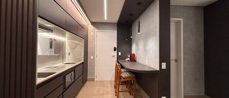 Una cocina moderna con horno empotrado, lavamanos y zona de comedor con sillas.