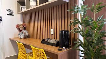 A modern kitchen with a wooden countertop, two yellow chairs, a black coffee maker, and a potted plant.