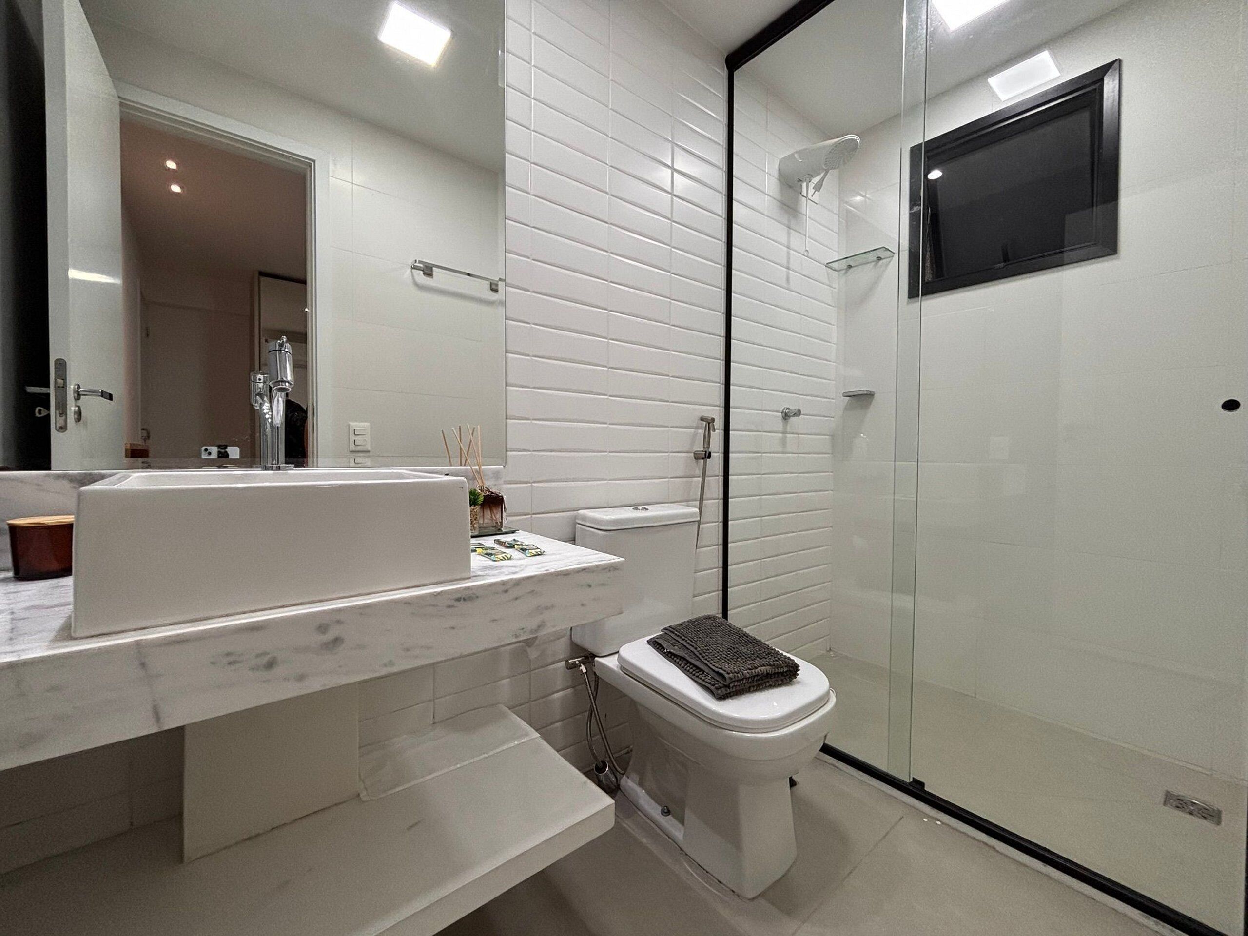 Une salle de bain moderne avec un lavabo blanc, des toilettes et une douche à parois de verre.