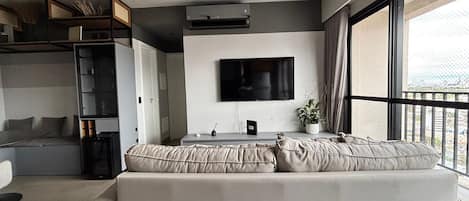 Una sala de estar moderna con un sofá, un televisor y vistas al balcón.