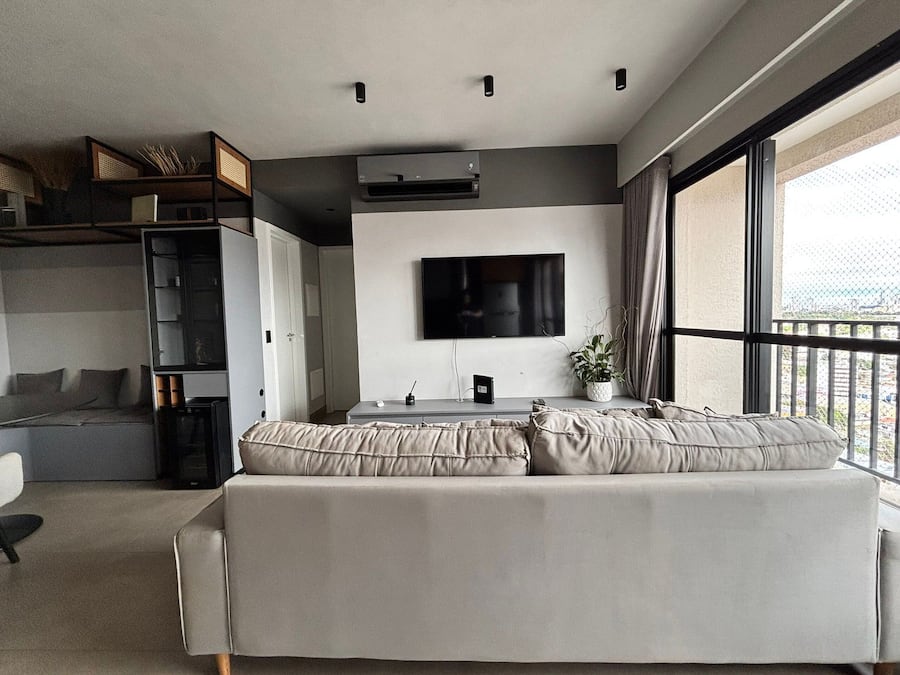 A modern living room with a sofa, a TV, and a balcony view.