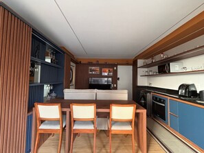 A compact living space with a dining area, kitchenette, and a sofa. - ID Vida Urbana (Goiânia)