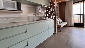 Una cocina moderna con microondas integrado, cafetera y un panel de madera.