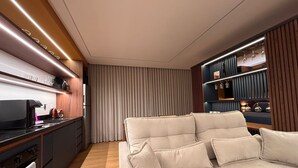 Una sala de estar moderna con sofá, una cocina con electrodomésticos y un comedor con mesa y sillas.