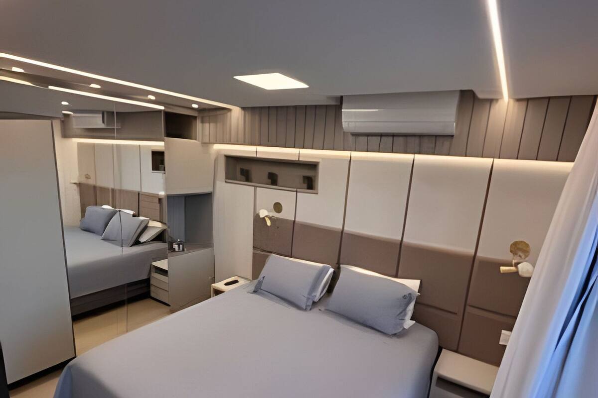 A modern bedroom with a large bed, bedside tables, a mirror, and built-in storage.