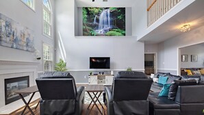 Un salon moderne avec une cheminée, un téléviseur fixé au mur et un ensemble de canapés.