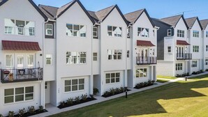 Fileira de prédios de apartamentos modernos, com varandas e um gramado bem cuidado.