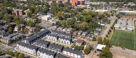 An aerial view of a residential area with houses, a large building with a red roof, and a sports field.